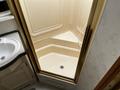Interior shower area of a 2000 Ford Motorhome featuring a beige shower base and framed glass doors