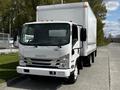 A white 2016 Isuzu NQR box truck with a large enclosed cargo area in the back and a sleek front design parked on a pavement road