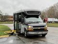 A 2020 Chevrolet Express bus with a wheelchair ramp deployed and doors open, showcasing a grey exterior and front grille with a Chevrolet emblem