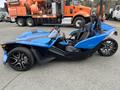 A blue 2020 Polaris Slingshot three-wheeled motorcycle with a sporty design and two seats visible from the side angle