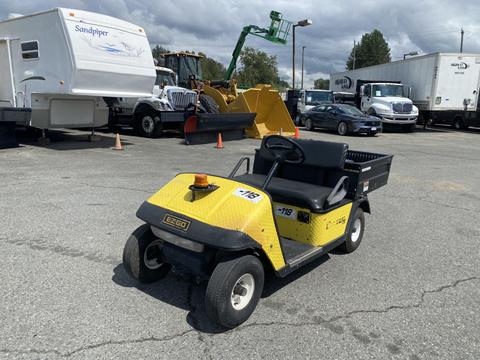 A yellow and black 1999 Ez-go Industrial vehicle with a flatbed and a single seat featuring a warning light on top