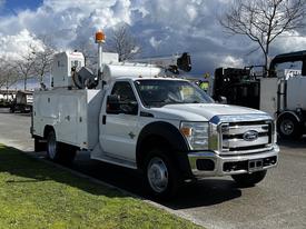 A 2016 Ford F-550 service truck with a white body and a utility bed featuring equipment and tools on top and a light on the cab