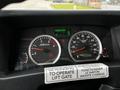 Dashboard of a 2018 Isuzu NRR showing gauges for RPM and speed along with various warning lights and an instructions sticker for operating the lift gate