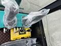 Control levers of a 2024 AGT Industrial Green QH13R Mini Excavator covered in plastic with a toolbox visible below