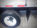 A close-up of the tire and wheel of a 2016 International WorkStar 7500 truck showing a black mud flap attached to the vehicle