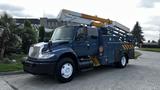 A blue 2009 International 4300 utility truck with a lift arm and equipment compartments on the side