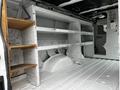 Interior of a 2009 Ford Econoline van featuring wooden shelving on one side with storage space and a partitioned area at the rear