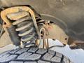 Close-up of the undercarriage of a 2016 Ford F-350 SD showing the suspension system with a prominent coil spring and a portion of the tire tread