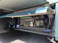 A generator labeled Onan Marquis 5500 is positioned under the side of a 2000 Ford Motorhome with visible wiring and paneling