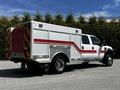 A 2009 Ford F-550 emergency service vehicle with a white and red body and a utility box on the back with reflective stripes