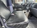 Interior view of a 2008 Mitsubishi Fuso FE180 showing two leather seats with seatbelts and a central dashboard area with controls and storage compartments