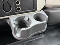 A gray cup holder with two openings, designed to hold cups or drinks, featuring a textured surface and a molded design, mounted in a vehicle dashboard