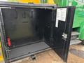 A black storage compartment of a 2015 Freightliner M2 106 truck with a door open showing hooks and a red device inside