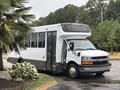 A 2020 Chevrolet Express shuttle bus with a white exterior and large windows parked on a street