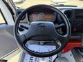 A black steering wheel with a logo in the center is shown inside a 2018 Hino 195 truck cab along with visible dashboard gauges and controls