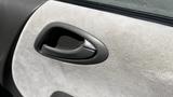 Interior door handle of a 2006 Honda Fit in a light-colored fabric trim