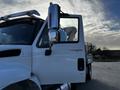 A 2013 International DuraStar 4300 truck with a white exterior and a chrome side mirror positioned at an angle showing the driver's seat and door handle