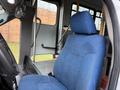 A blue upholstered driver's seat in a 2011 Ford F-550 with a steering wheel and dashboard visible in the foreground