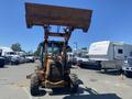 A 2008 Case Super 580M backhoe loader with a raised front bucket and large tires positioned in a parking lot