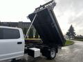 A white 2021 Ford F-550 truck with a raised dump bed revealing a black interior and hydraulic lift system