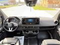 Interior view of a 2019 Mercedes-Benz Sprinter featuring a steering wheel dashboard and central console with infotainment system and cup holders