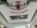 A ceiling hatch in a vehicle labeled as an emergency exit with instructions in English and French on how to open it