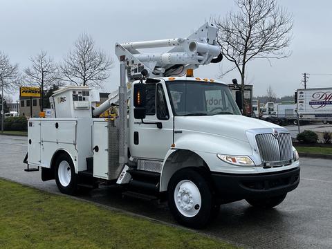 A white 2013 International DuraStar utility truck with a hydraulic lift and a storage compartment on the side