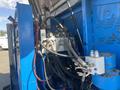 Close-up of hydraulic components and hoses on a 1997 Genie S-65 4X4 showing multiple valves and connections in a blue metal casing