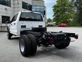 A 2024 Ford F-550 chassis cab with a white exterior and large black tires showing the rear view and exposed frame components