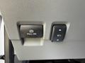 Close-up of a dashboard panel featuring a pull-on parking brake button and an adjustable seat control button in a 2023 Ford F-550