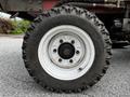 A close-up of a 2012 Toro Groundsmaster's tire showcasing its rugged tread and white rim with multiple bolts and the text All Trail