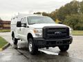 A white 2015 Ford F-350 SD with a utility body and black front grille parked on a wet surface