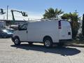A white 2019 GMC Savana van is parked with its side facing forward and a ladder rack mounted on the roof