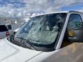 A 2012 GMC Savana van with a clean windshield reflecting clouds and sunlight