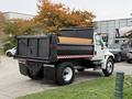 A 2006 International 4200 dump truck with a black bed and wooden sides parked in a lot