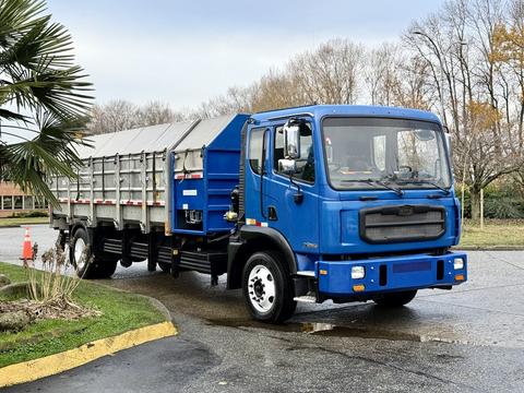 A blue 2017 Autocar Xpert truck with a flatbed and rear dumping feature is parked with its cab facing the viewer