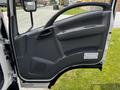 The interior door of a 2016 Isuzu NQR showing the control panel and handle in gray plastic material