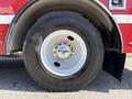 A close-up of a large black tire mounted on a red truck with a white rim and visible tread pattern