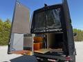 A 2017 Mercedes-Benz Sprinter with its rear doors open revealing an organized interior featuring storage cabinets and a counter workspace.