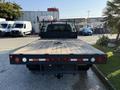 2014 Ford F-550 flatbed truck with a black bed and visible taillights positioned in the foreground