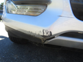Close-up of the front bumper of a 2015 Ford Escape showing scratches and scuff marks on the lower edge
