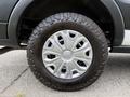 A close-up of a tire from a 2022 Ford Transit featuring an intricate silver wheel design and rugged black tread pattern