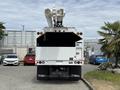 A white 2020 Freightliner M2 bucket truck with two extended lift arms attached at the rear and a large empty cargo area visible