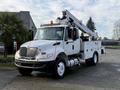 A white 2013 International Durastar 4300 utility truck with a cherry picker mounted on the bed and storage compartments on the side
