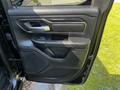 The interior door panel of a 2019 RAM 1500 featuring a black finish a silver door handle buttons for controls and a textured armrest