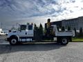 A 2013 International DuraStar 4300 flatbed truck equipped with a crane on the rear and side tools displayed