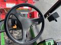 Close-up of the steering wheel of a 2014 John Deere 1585 Terrain Cut with control levers and dashboard visible