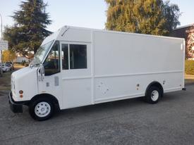 A white 2006 Ford Econoline cargo van with a boxy design and large side windows on the passenger side