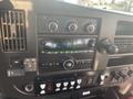 The interior dashboard of a 2018 Chevrolet Express featuring climate controls a radio display and various buttons and knobs for vehicle settings