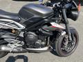 A 2018 Triumph Street Triple RS motorcycle with a matte gray finish and red accent details featuring a sleek design and exposed engine components